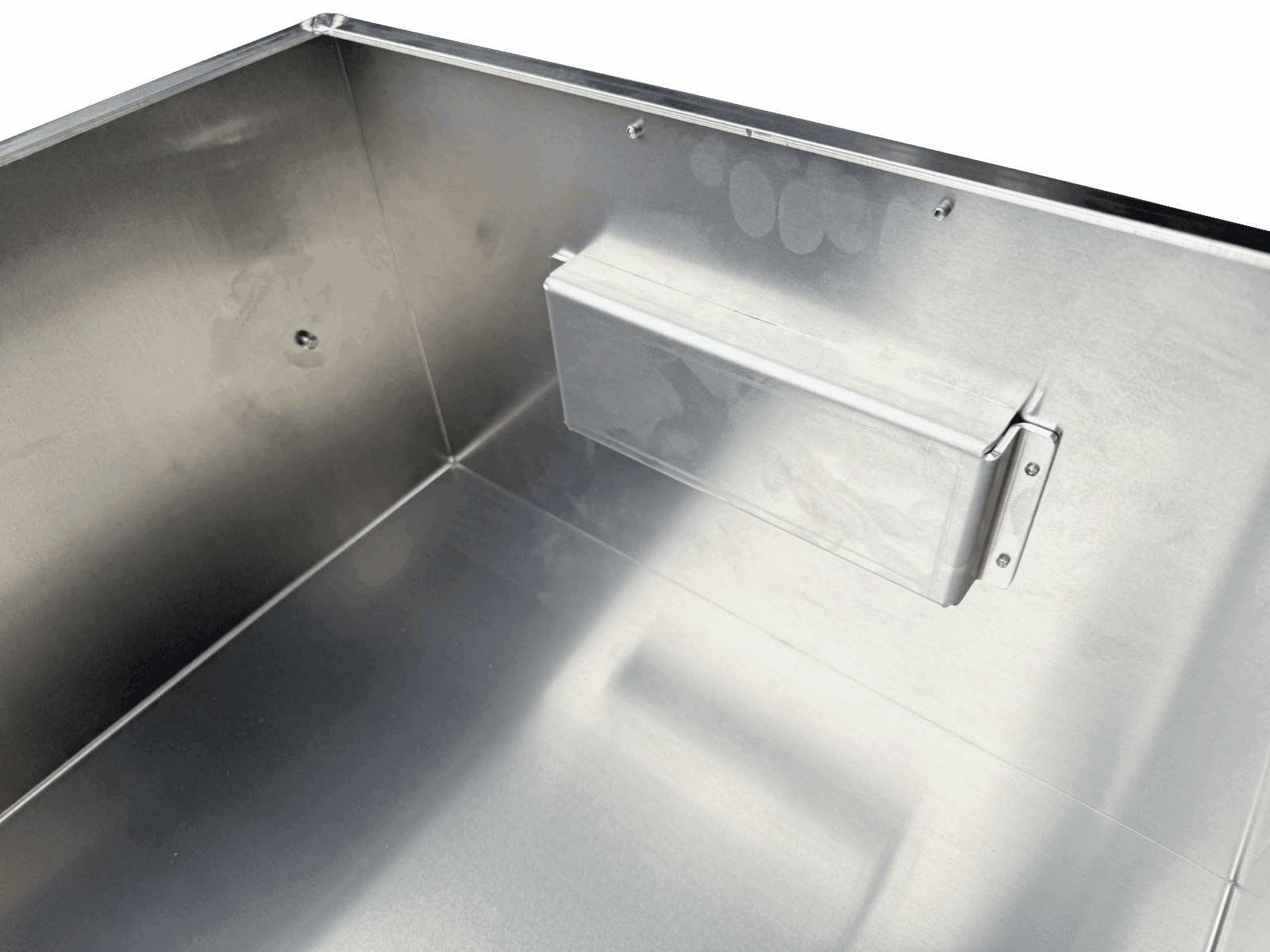 Interior corner of a brushed metal enclosure with a screw-mounted rectangular component.